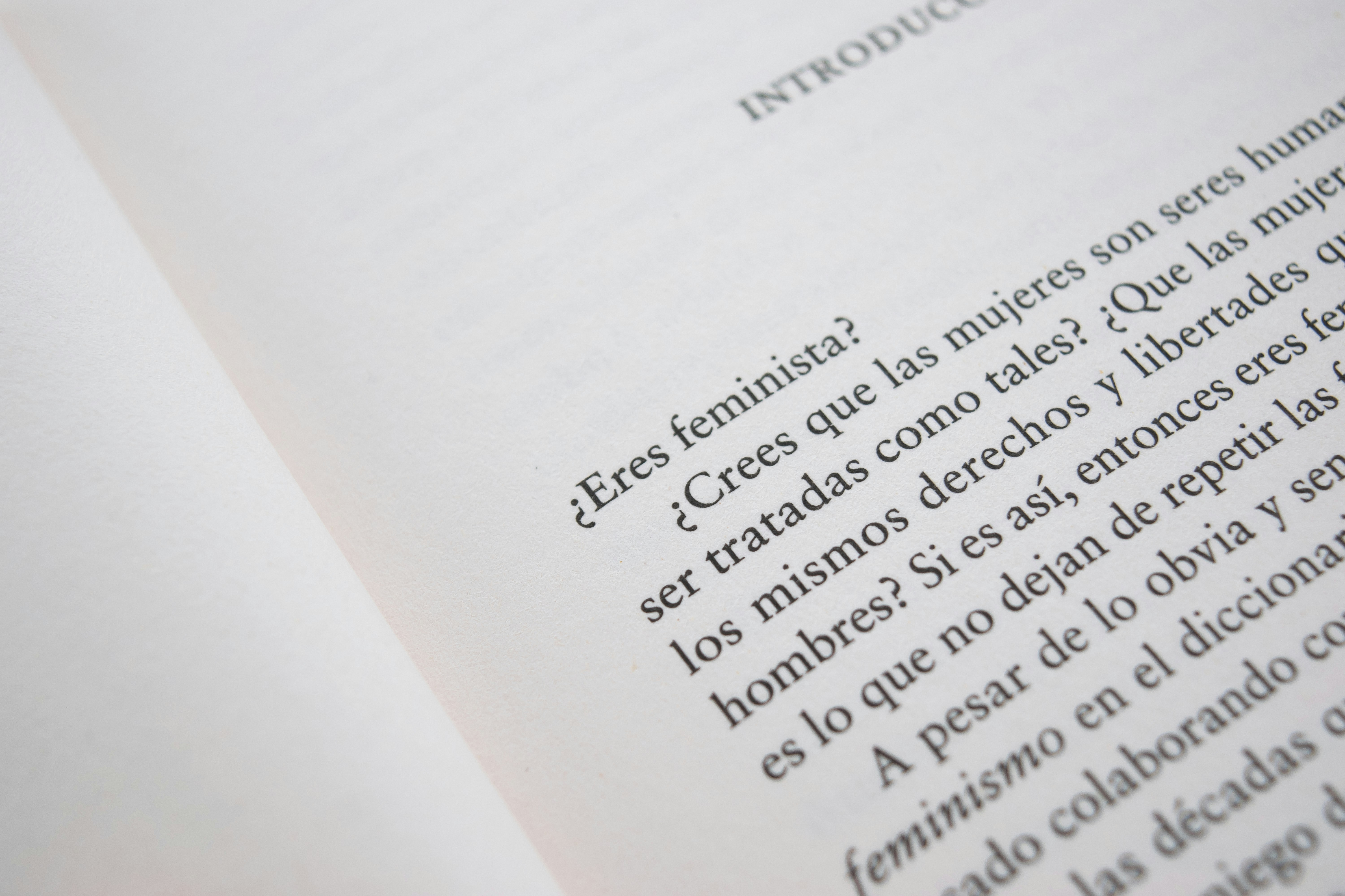 公園のベンチで、イヤホンをつけてオーディオブックを聴きながら読書している女性